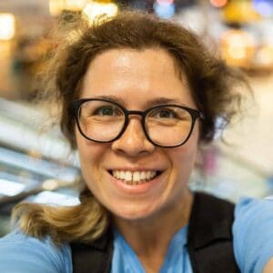 Fröhliche Frau mit Brille in urbaner Umgebung, strahlendes Lächeln, Mode und Lifestyle.